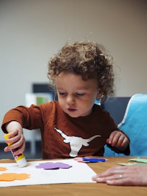A child glues a shape to paper
